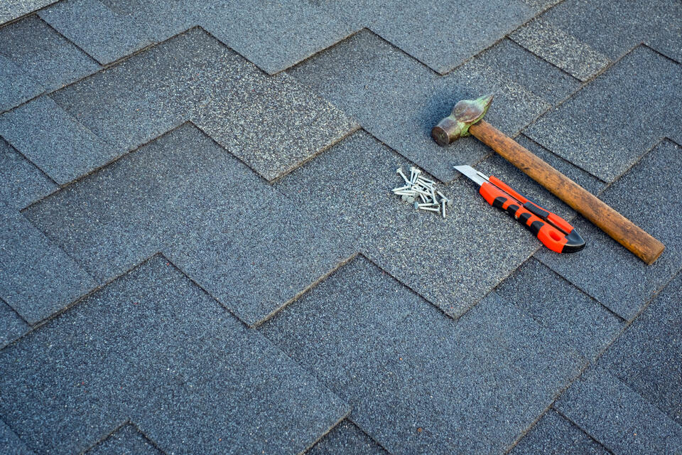 roofing tools-roofing hammer, knife, and nails gathered on a shingle roof