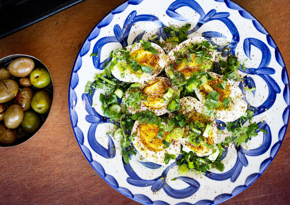 extra virgin-blue and white plate serving deviled eggs and greens