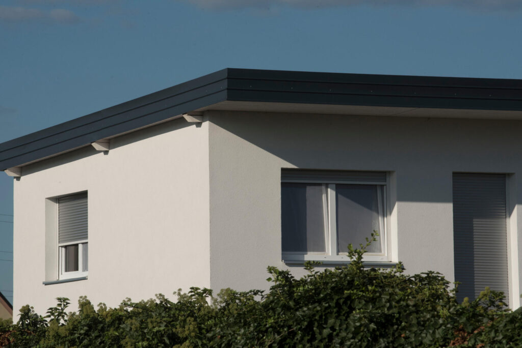 modified bitumen roofing-white house with a black flat roof and shrubbery surrounding the house