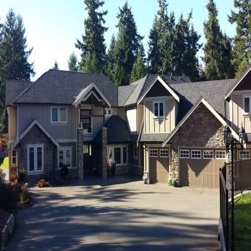 Shamrock Roofing and Construction residential home with new roof and siding in a wooded area.