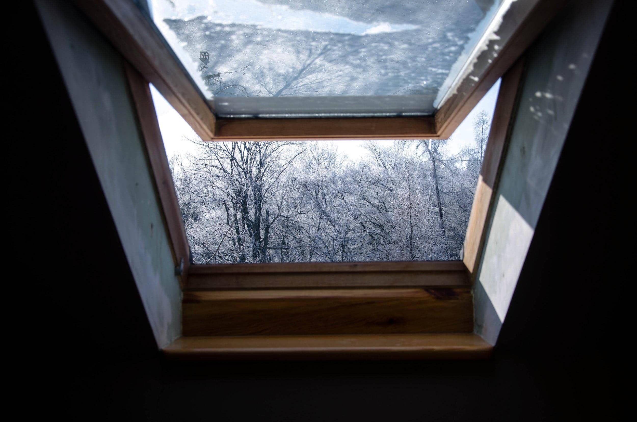 Roof window with snowy trees view, residential roofing, and construction details.