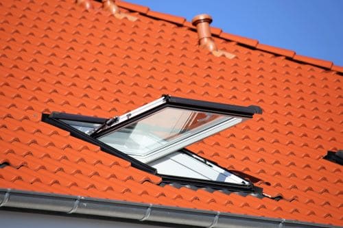 Efficient roof ventilation with a skylight on a red tile roof for improved airflow and natural light.