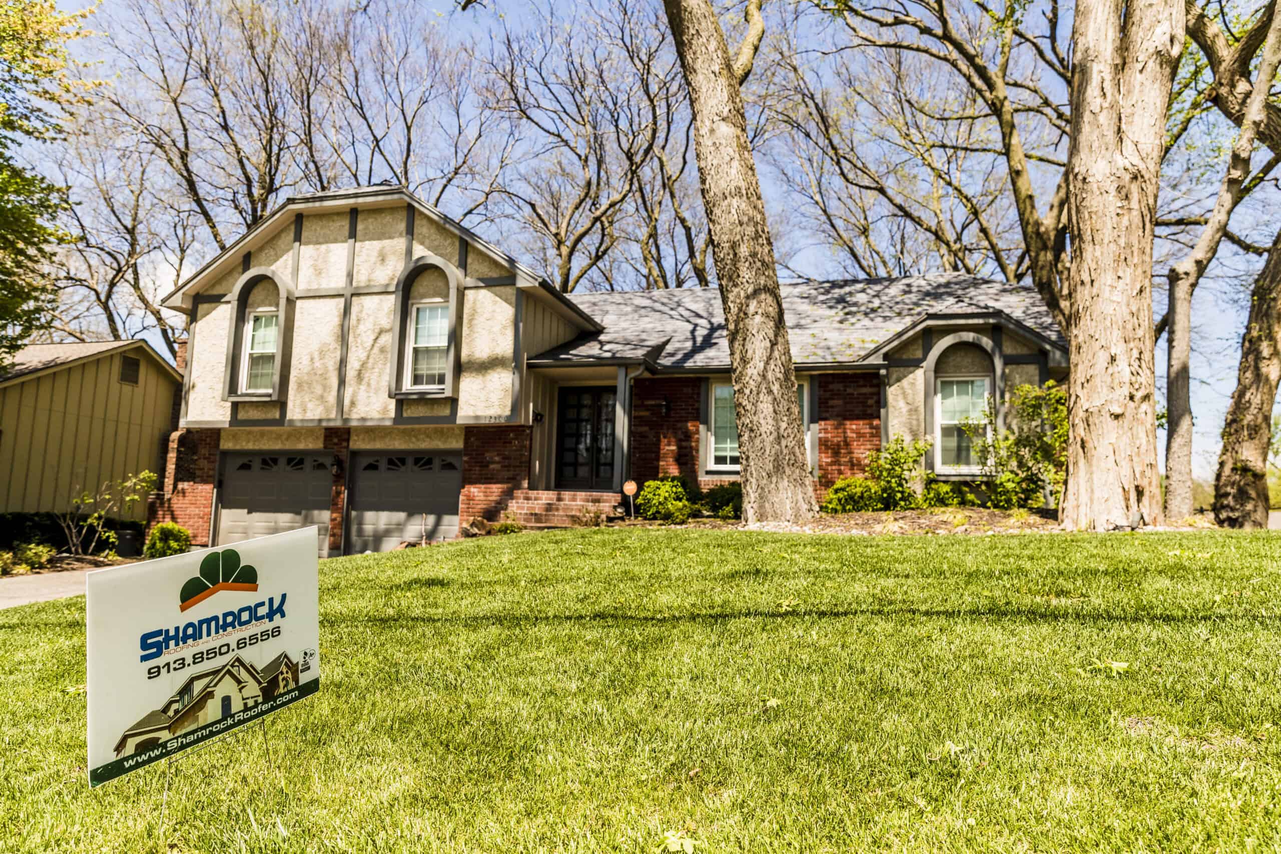 Gable roof house with attached garage and front yard for roofing and construction services.