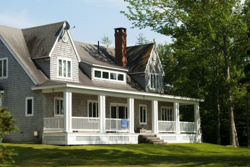 Shamrock roofing and construction exterior of residential home with new roofing and large porch installed in a lush green yard.