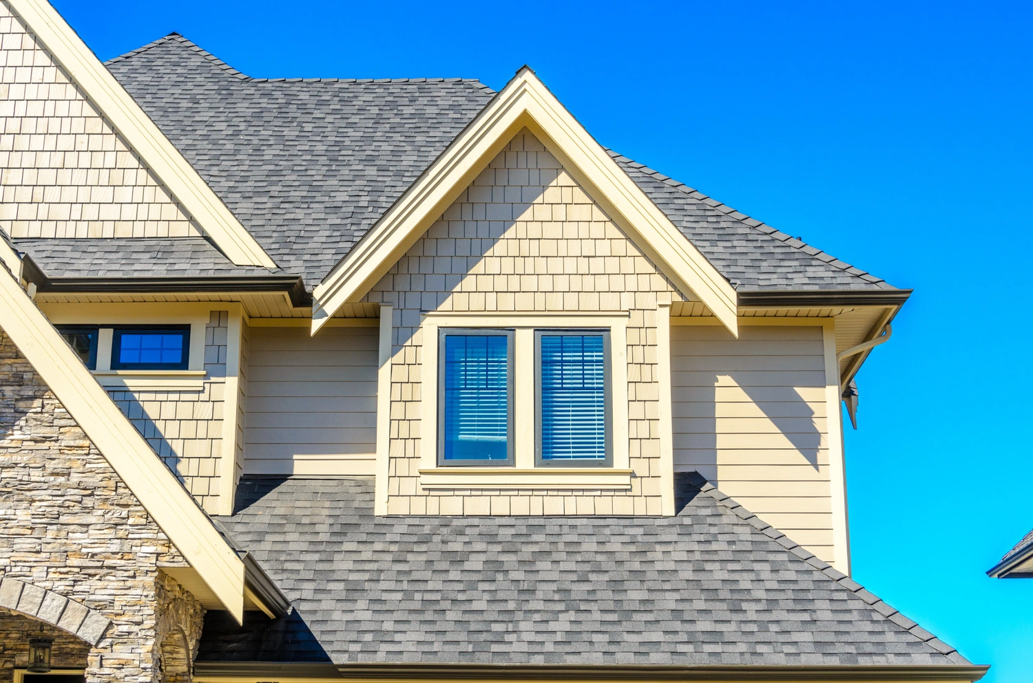 outside view of the top right corner of a yellow residential house with windows and a blue sky