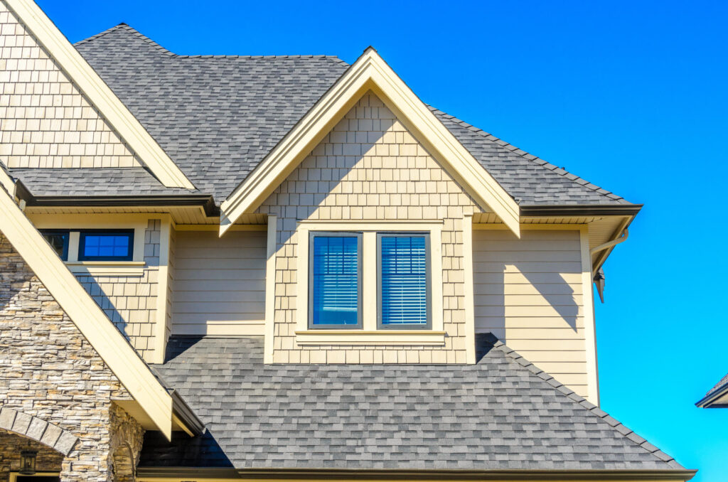 roofing des moines ia-cream and stone sided house with gray shingled roof