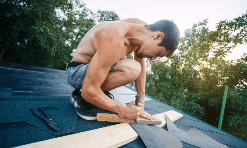 Man installing roofing shingles on a house roof, roofing construction, Shamrock Roofing and Construction.