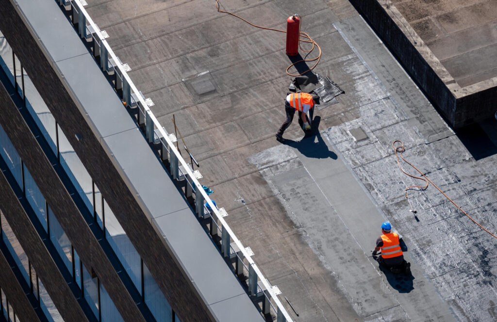 how to seal a flat roof-aerial view of a commercial flat roof with a crew working on sealing the surface