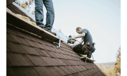 Roofers installing shingles on a residential roof in the process of roofing and construction.