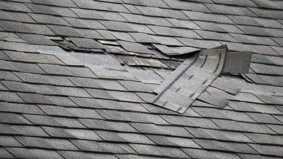 Damaged roof shingles with missing and broken tiles, requiring roofing repair services.