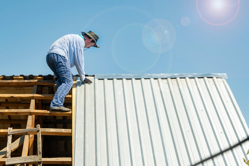 benefits of metal roofing-white metal roofing panels being installed on a home