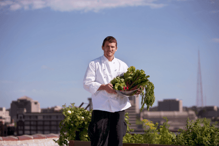 Friendly roofing and construction professional holding green foliage on rooftop.