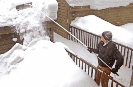Heavy snow removal from residential roof in winter weather, emphasizing roofing and construction services.