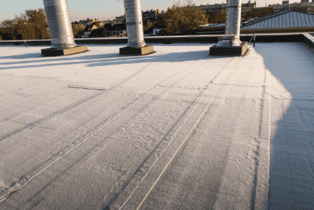 Storm-resistant flat roof with roofing membrane, vents, and skylights.