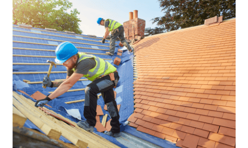 Shamrock roofing and construction workers installing new roofing shingles on residential house.