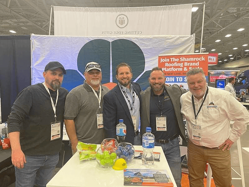 Shamrock roofing construction team at trade show outdoor booth.