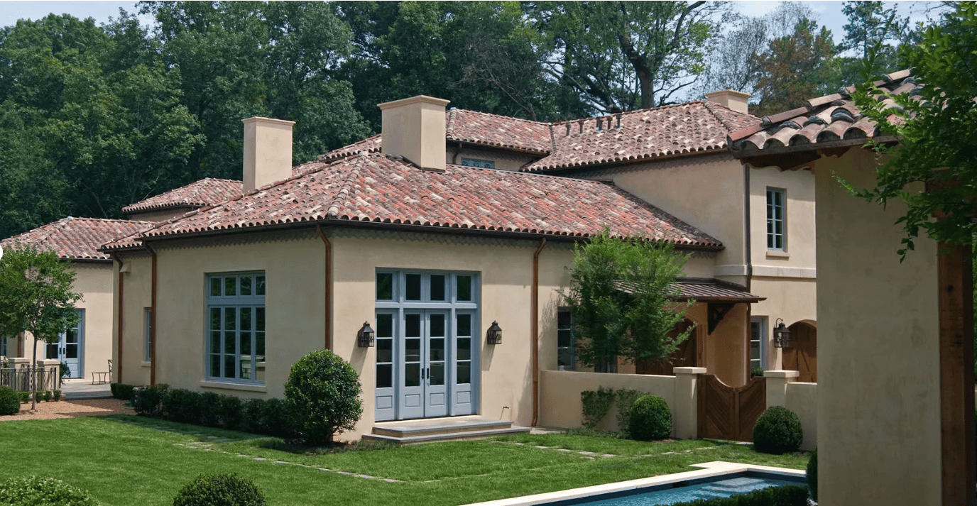 Elegant Mediterranean-style home with clay tile roof and lush landscaping, showcasing professional roofing craftsmanship.