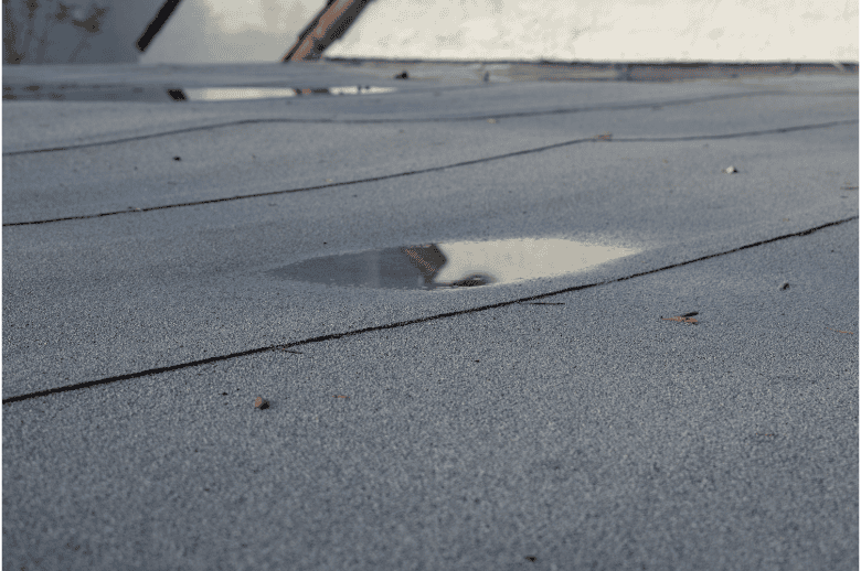 Pothole repair on asphalt roof with standing water, roof leak damage, and roofing maintenance.