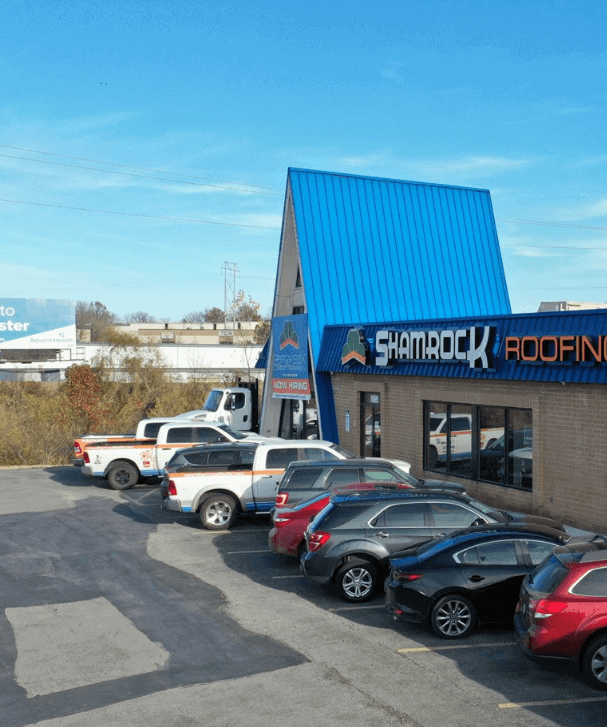 Shamrock roofing and construction building with roof logo and parking lot.