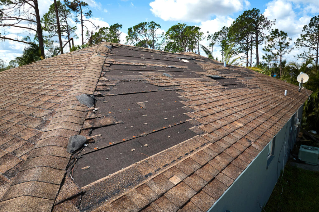 does homeowners insurance cover roof replacement-storm damaged house roof with missing and damaged roof shingles