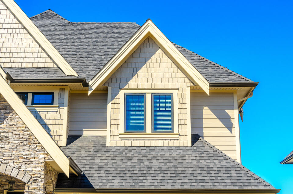 Shamrock roofing-cream and stone sided house with gray shingle roof