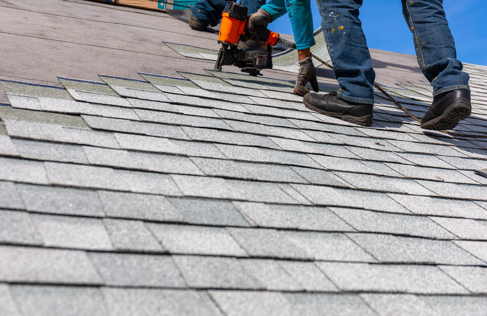 how long does it take to replace a roof-close up of roofers on a roof installing new shingles