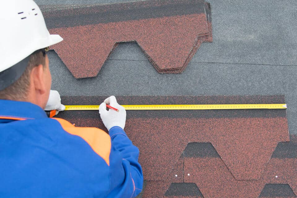 how to measure a roof for shingles-roofer using a measuring tape and pencil to measure roof shingles