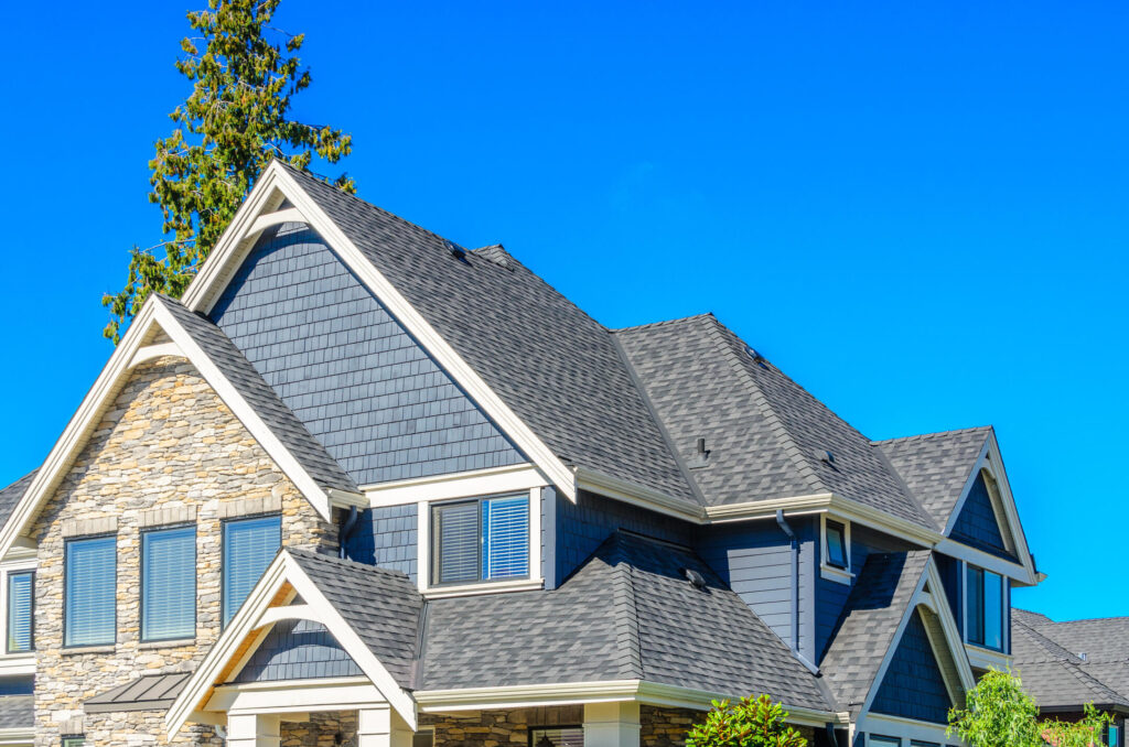 metal roof vs shingles cost-blue and stone sided house with gray shingle roof