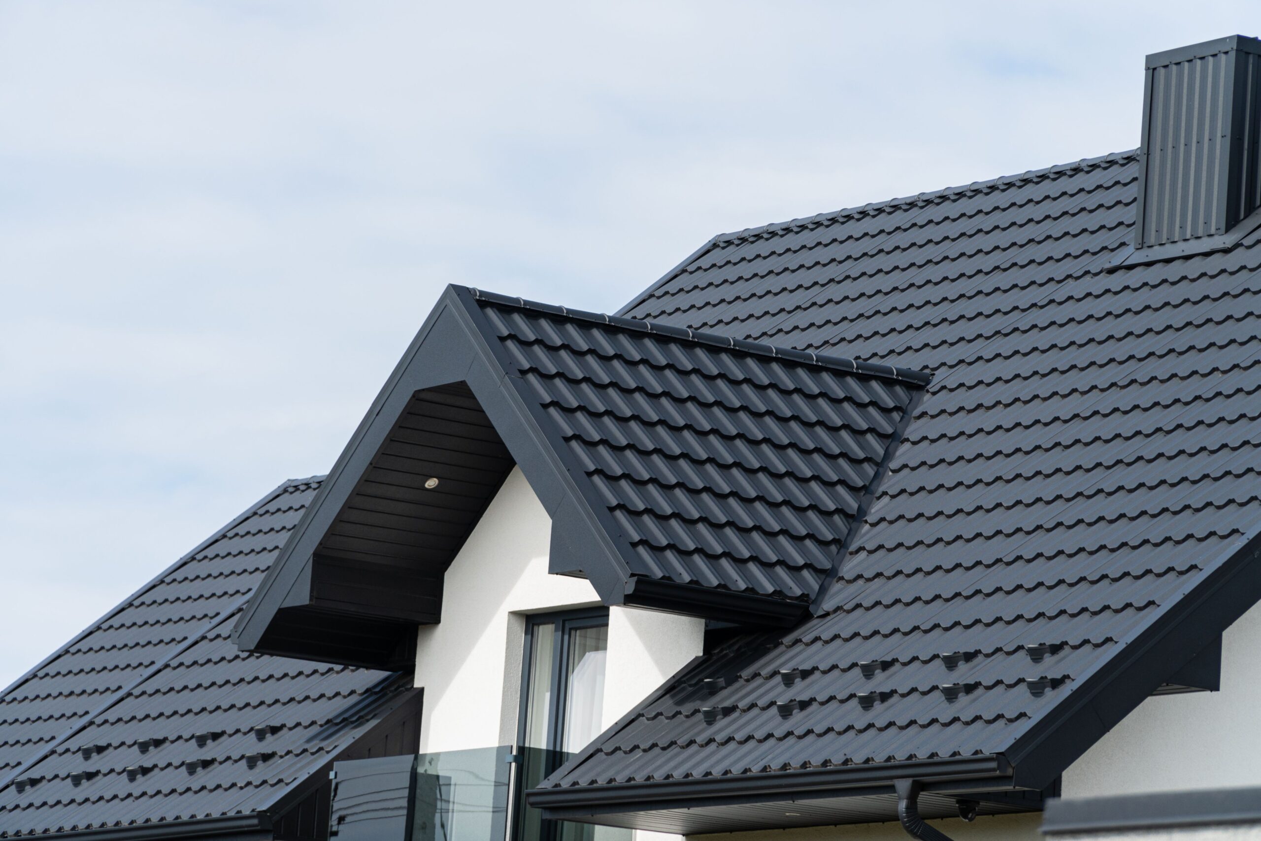Modern home featuring black metal tiles after a professional roof replacement Liberty project